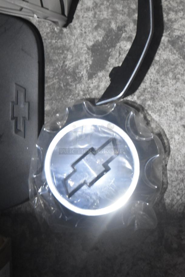 Brand new lot of car parts, including car mats with Chevrolet logo in black poly bin; tags indicate authenticity.