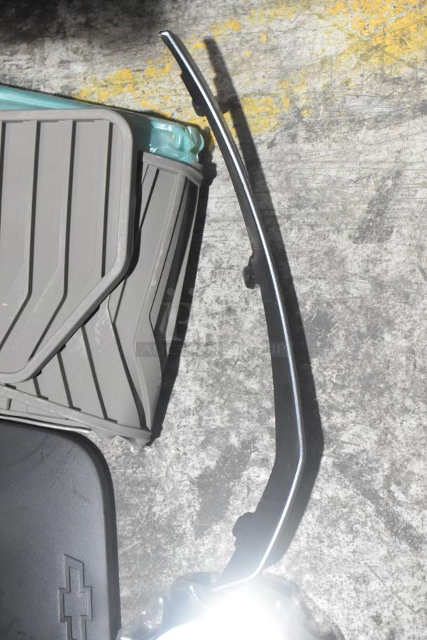 Brand new car parts lot including black car mats in a black poly bin, feature branded logo detail, ready for use.