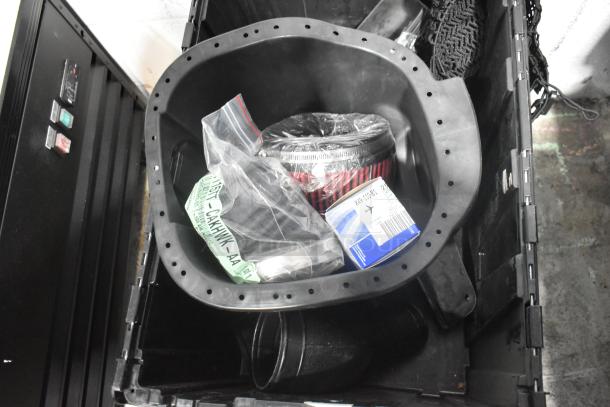 Black poly bin containing a brand new lot of various car parts, including panels. Visible labels and packaging.