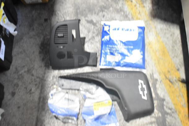 Lot of brand new car parts including black panels and accessories in poly bin; visible Chevy logo on one piece.