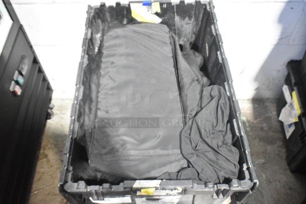 Brand new car parts in black poly bin, featuring Corvette bags. Bin shows various tags and labels for identification.