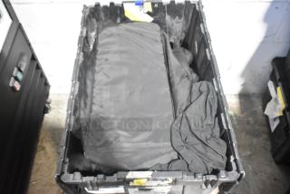 Brand new car parts in black poly bin, featuring Corvette bags. Bin shows various tags and labels for identification.