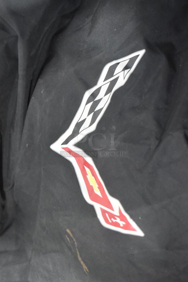 Brand new Corvette bag with logo on black fabric, part of various car parts in a black poly bin.
