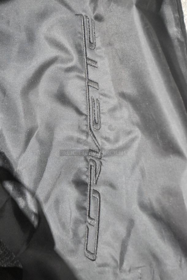 Black Corvette bags with embroidered logo, part of a brand-new lot of various car parts in a poly bin.