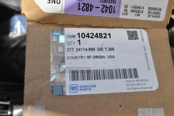 Brand new GM car parts including GM 10424821 grille assembly box with label, quantity 1, made in USA, in black poly bin.