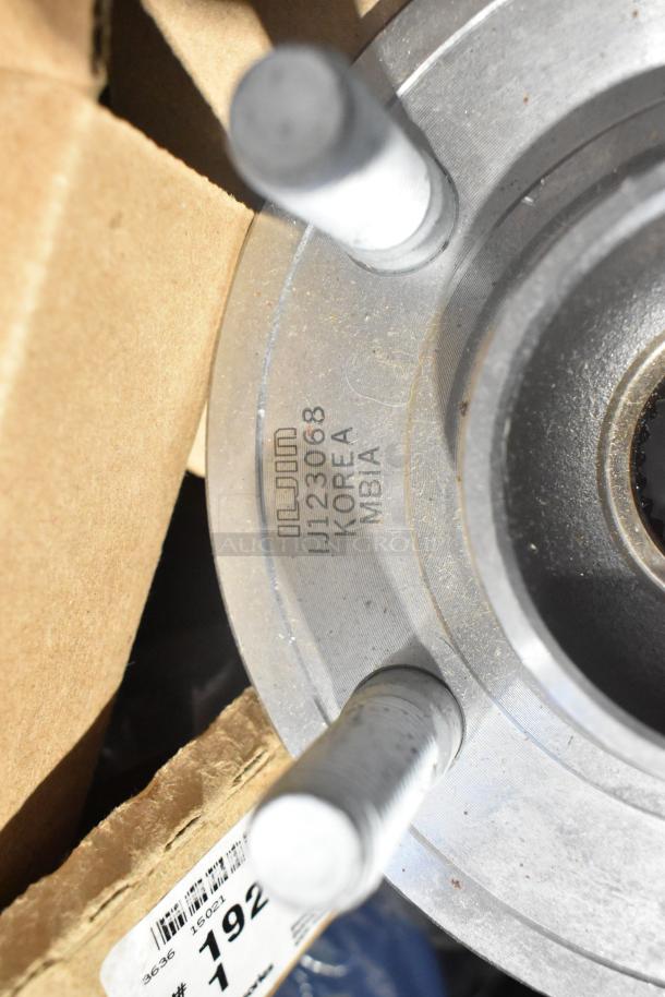 Lot of new car parts including GM 10424821 grille, GM 19201541 lug nuts, and GM 19244300 cargo net in black bin.