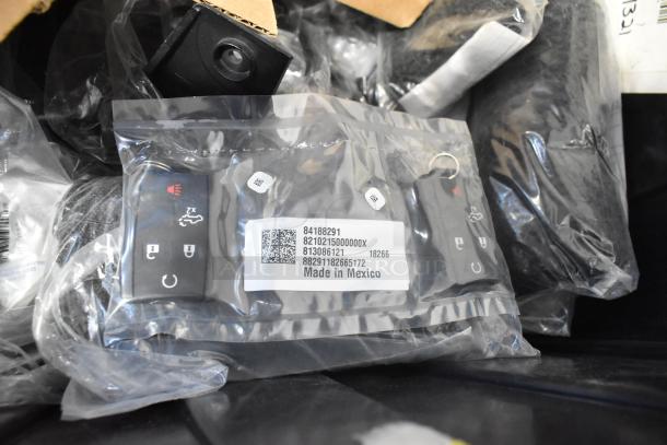 Lot of new car parts in black poly bin, includes GM 10424821 grille assembly, GM 19201541 lug nuts, GM 19244300 cargo net.
