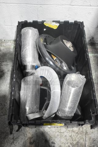 Brand new car parts including Corvette steering wheels in a black poly bin, wrapped in protective packaging. Tags visible.