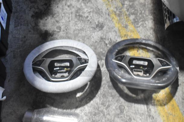 New Corvette steering wheels in protective covers, placed on concrete. Includes visible labels and wiring details.