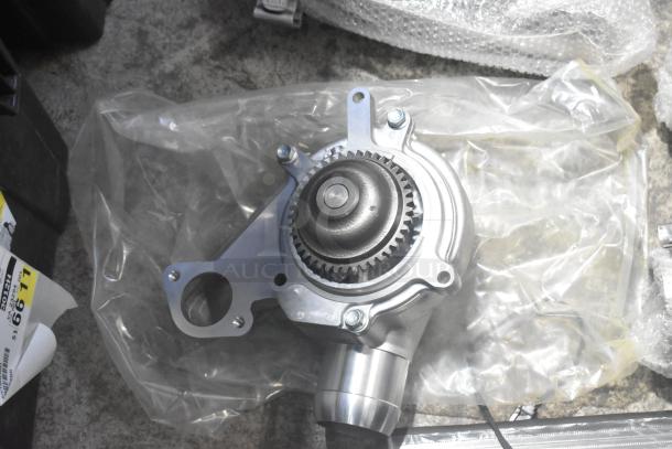 A new car part with gears and mounting holes, packaged in a clear bag. Part of a lot including Corvette steering wheels.