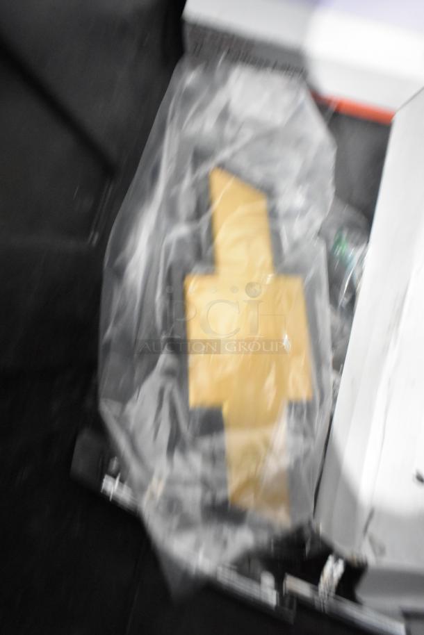 Assorted new car parts including a Corvette steering wheel, packaged in a black poly bin, visible labels on parts.