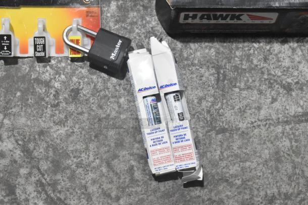 Lot of new car parts including Hawk Racing brake pads, two ACDelco lacquer touch-up paints, and a Master lock.