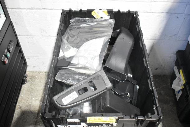 Lot of brand new car parts including telephone, panels in black poly bin. Includes labels with barcodes and item numbers.