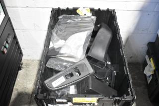 Lot of brand new car parts including telephone, panels in black poly bin. Includes labels with barcodes and item numbers.