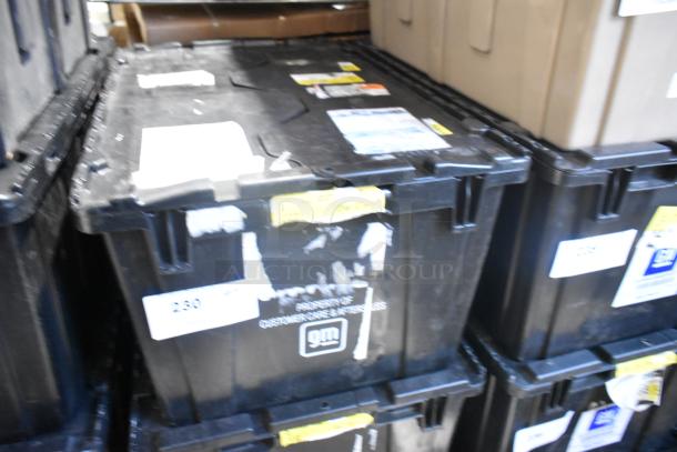 Black poly bin containing brand new car parts, including a telephone and panels. GM markings visible on bin surface.