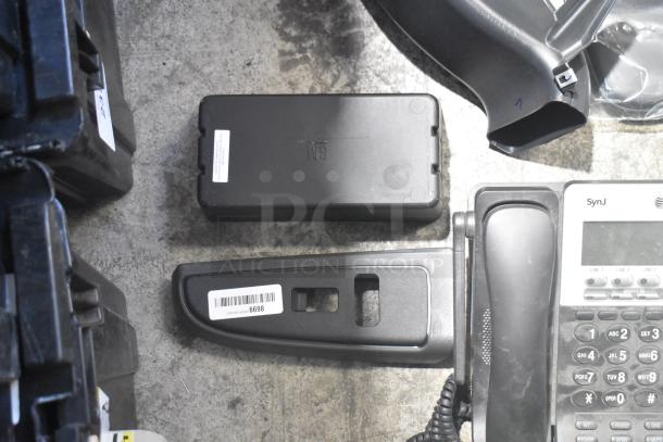 Lot of various new car parts including a telephone and black panels in a poly bin. Labels and part numbers visible.