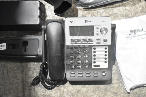 Brand new lot of car parts in a black poly bin, includes an AT&T SynJ telephone. Tags show item numbers and details.