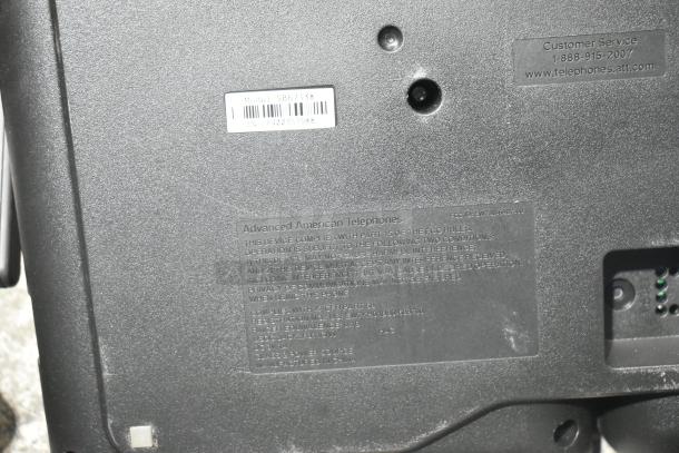 Black poly bin containing various car parts and a telephone. Telephone model SB67138 by Advanced American Telephones.