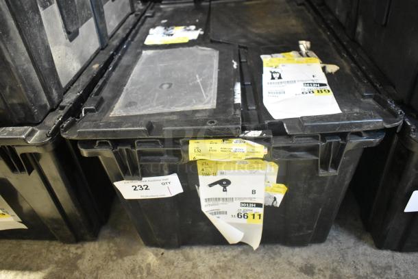 Black poly bin containing various new car parts, including a steering wheel and light panels. Visible labels with inventory details.