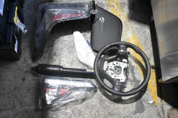 Brand new car parts, including a steering wheel and light panels, in black poly bin. Labels indicate unused condition.