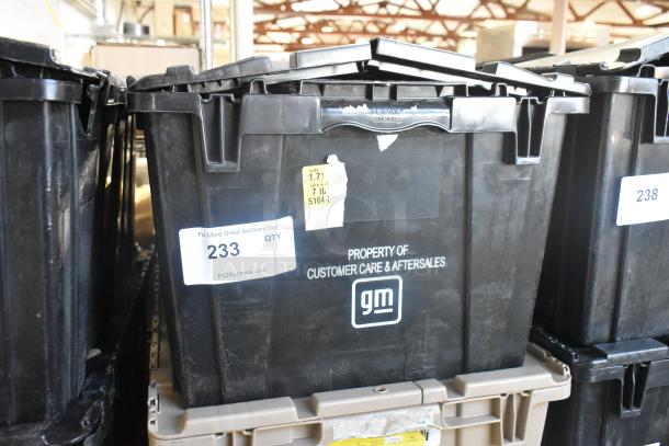 Black poly bin labeled "Property of Customer Care & Aftersales GM" containing brand new car parts, including spark plugs.