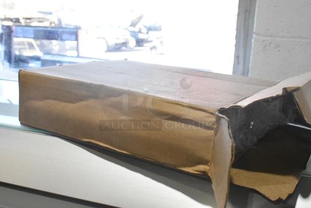 Cardboard box containing a lot of various brand new car parts including spark plugs, housed in a black poly bin.