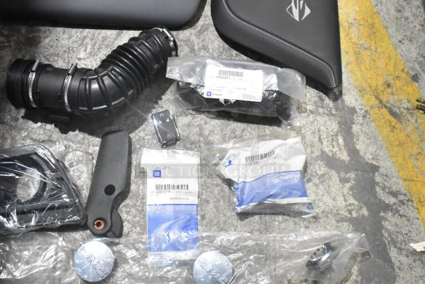 Lot of brand new car parts including spark plugs, GM packaging, and various components in a black poly bin.