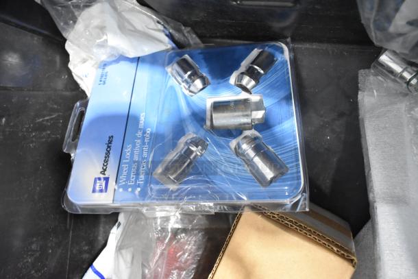 Brand new GM wheel locks in packaging within black poly bin, part of a lot including GMC emblems.