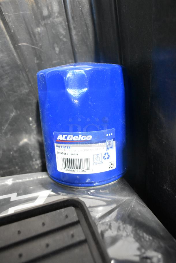 New ACDelco oil filter PF1218, blue with label in black poly bin alongside black car mats.