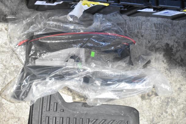 Brand new car parts lot, including car mats, packaged in a black poly bin. Items are sealed in protective plastic.