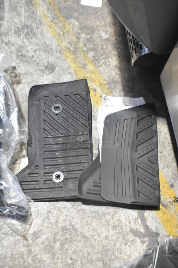 Brand new black car mats, various car parts in poly bin; visible textured design and mounting holes.