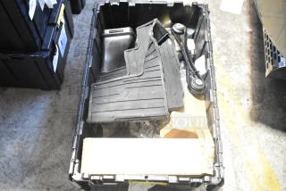Lot of brand new car parts including black car mats in a black poly bin.