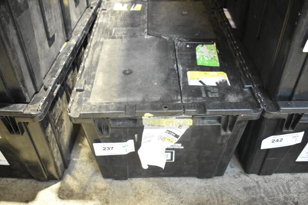 Black poly bin containing brand new car parts, including car mats. Visible labels indicate lot number and quantity.