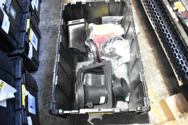 Brand new lot of various car parts, including car mats, in a black poly bin; tags not visible.