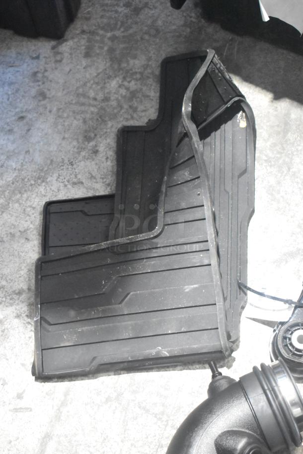Brand new black car mats in a poly bin, part of a lot of various car parts.