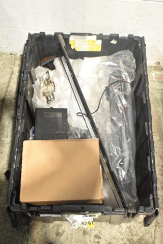 Lot of new car parts including GM 25958214 tail lamp assembly, emblems in a black poly bin. Tags and labels visible.