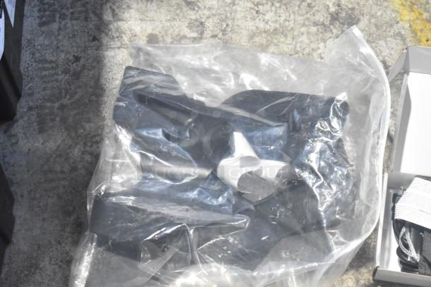 Brand new black poly bin with various car parts, including spark plugs and a grille, wrapped in clear plastic, on concrete floor.