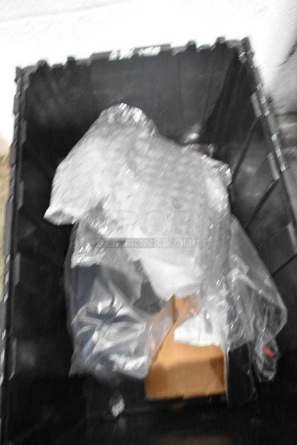 Brand new car parts lot in black poly bin, includes spark plugs and grille, wrapped in bubble wrap.