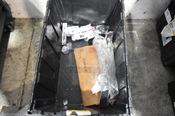 Brand new car parts including spark plugs and grille in a black poly bin with packaging and marked "Splash Thick."