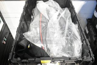 Brand new car parts in black poly bin, plastic-wrapped. Ideal for automotive needs. No visible labels.