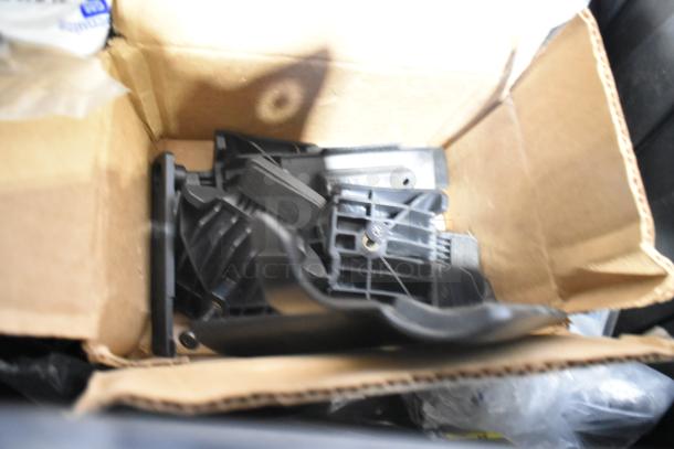 Brand new car parts in a cardboard box, including a Camaro-branded bag. Parts appear unused, packed in a black poly bin.