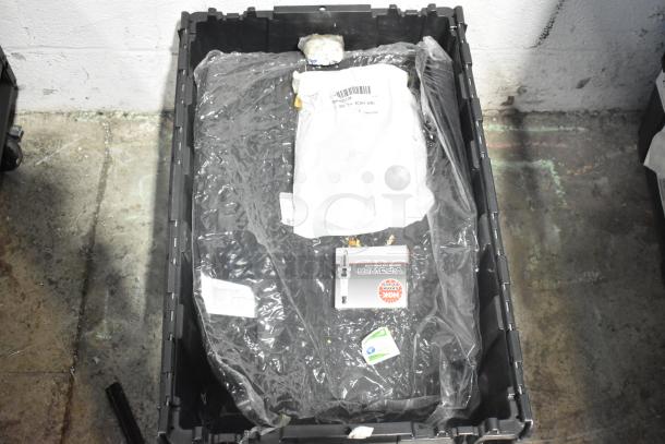 Brand new lot of car parts including spark plugs and a grille, in a black poly bin, with visible packaging and labels.