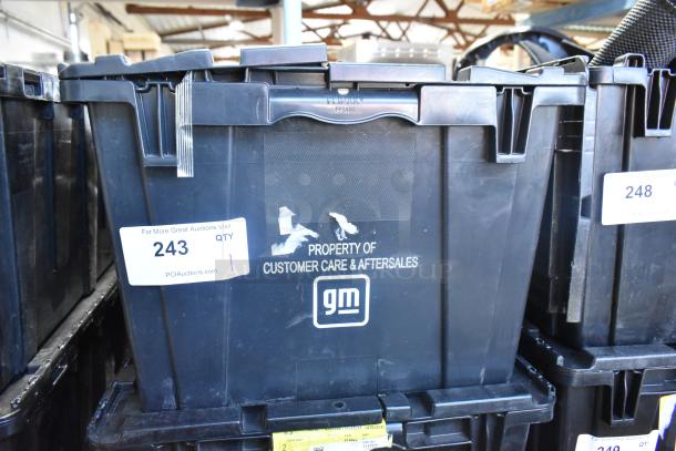 Black poly bin labeled "GM Property," holds various brand new car parts, including spark plugs and grille.