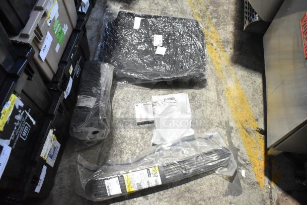 Brand new car parts including grille and spark plugs in black poly bin; items are in original packaging with labels visible.