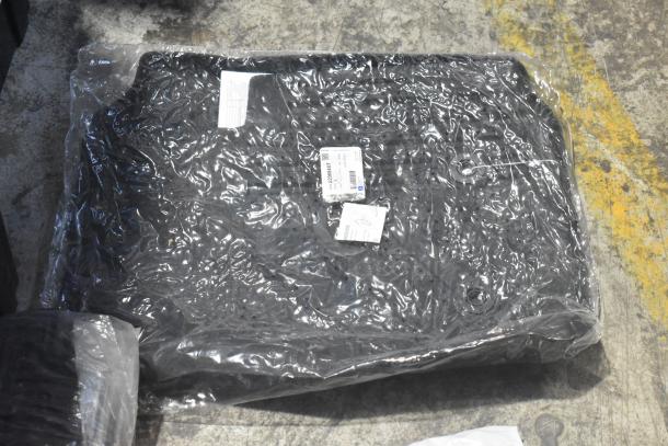 Brand new car parts lot including spark plugs and grille, in black poly bin. Parts in original packaging with visible labels.