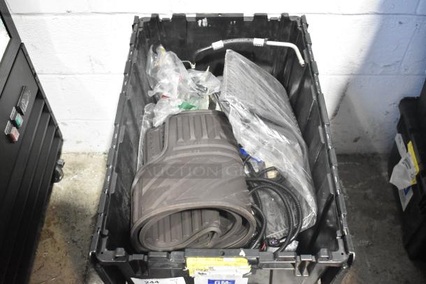 Black poly bin containing a lot of various brand new car parts including black car mats, wrapped cables, and pipe.