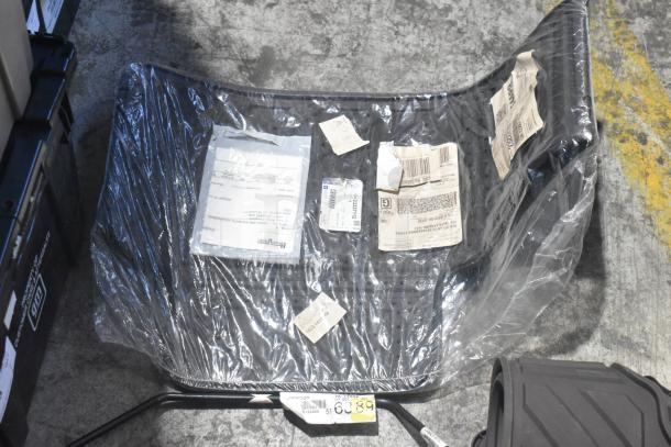Brand new car mats with visible labels in a black poly bin on a concrete floor. Tags include part numbers and barcodes.