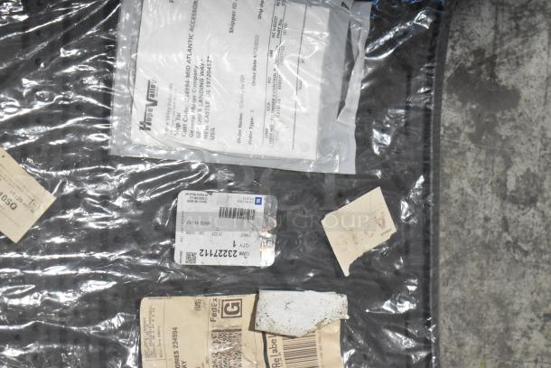 Lot of various car parts in black poly bin; labels display part numbers and GM branding. Condition: new.