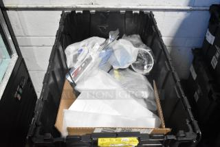 Brand new lot of various car parts in a black poly bin, including emblems and pouches. Items are wrapped in protective material.