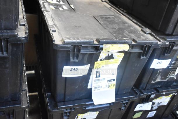 Black poly bin containing brand new car parts, including emblem and pouches. Visible labels with numbers and codes, indicating inventory details.